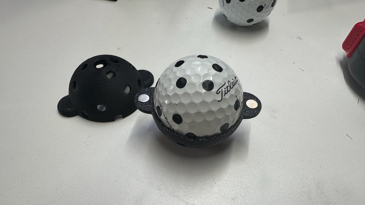 Geopend Square Golf markeersjabloon rond een golfbal met zwarte markeringen